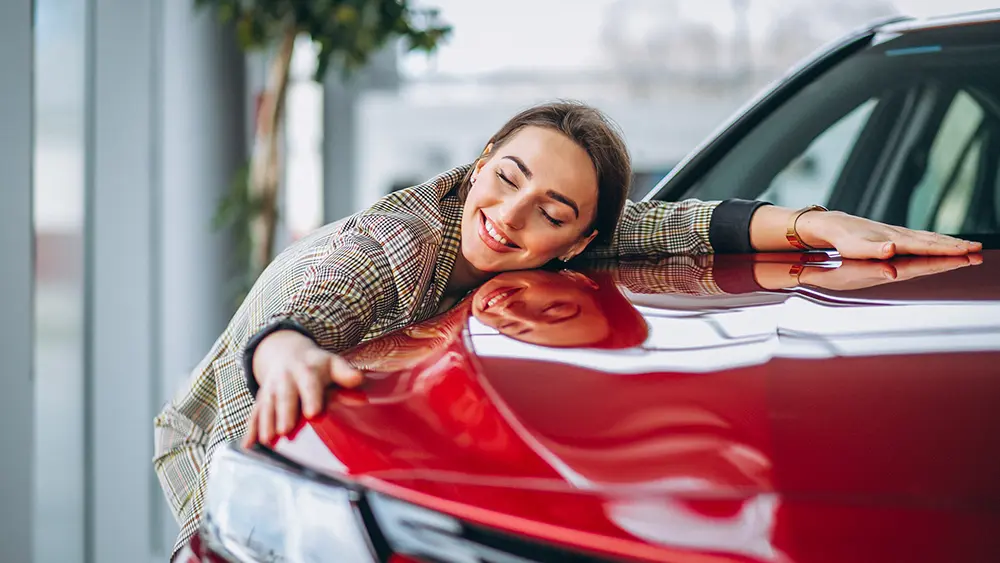 Schöne Frau, die ein Auto umarmt