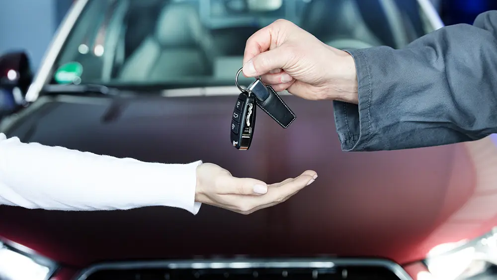 Der Leiter des Autohauses übergibt die Autoschlüssel an den neuen Besitzer.
